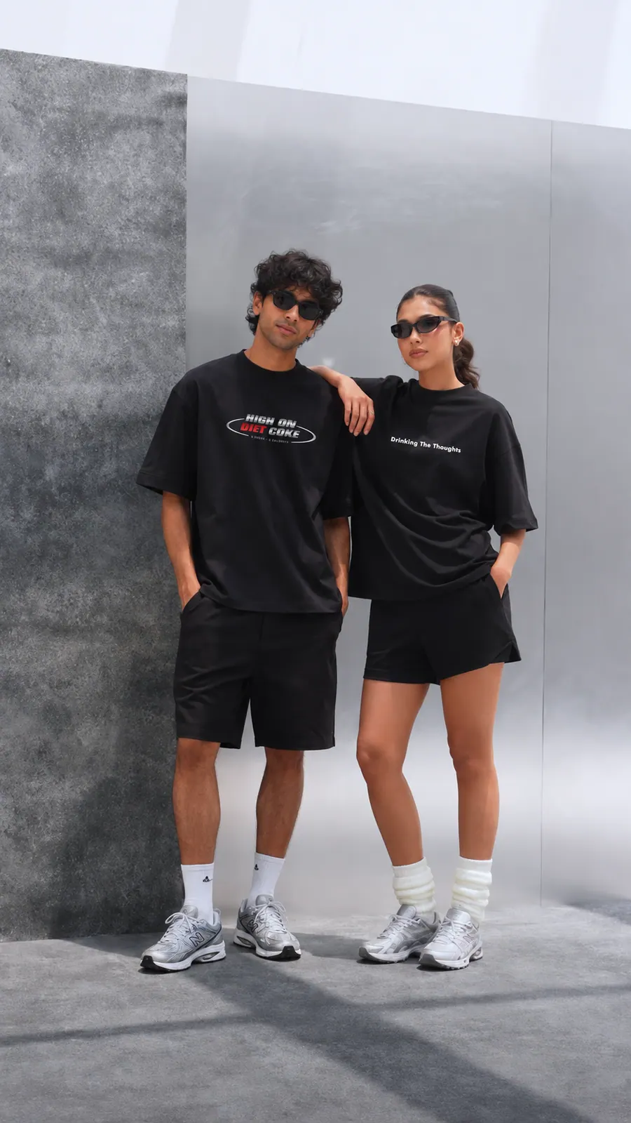 A still from a YAWI video ad: two models in matching YAWI tees against a concrete wall.