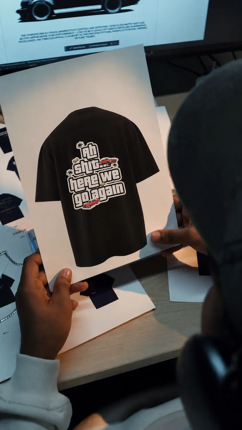 A frame from a YAWI reel: in the studio, a printed tee under the designer's hands.