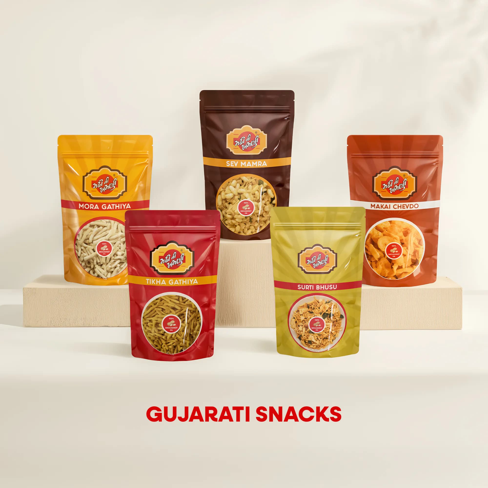 Five MNK farsan pouches on cream plinths: Mora Gathiya, Sev Mamra, Makai Chevdo, Tikha Gathiya and Surti Bhusu, above the words Gujarati snacks.