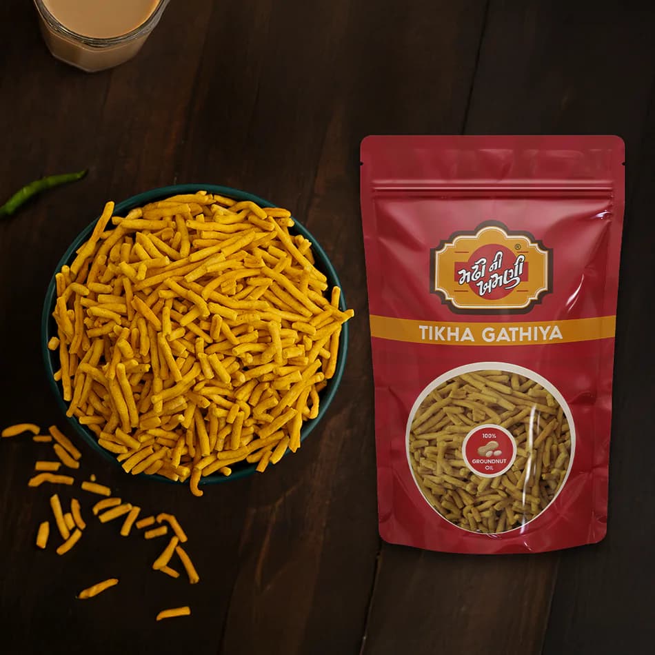 The Tikha Gathiya pouch beside a bowl of the spiced gathiya, on a dark wooden table.
